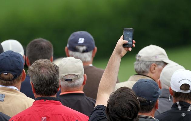 Un spectateur d'un tournoi de golf prend une photo à l'aide de son portable [Andy Lyons / Getty Images/AFP/Archives]