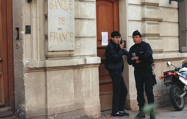 Un policier et un gardien surveillent l'accès de la Banque de France à Toulon le 17 décembre 1992, où a eu lieu un hold-up avec prise d'otages [Laurent Martinat / AFP/Archives]