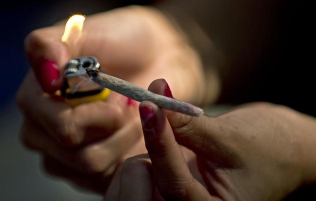 Une femme allume un joint de marijuana [Martin Bernetti / AFP/Archives]