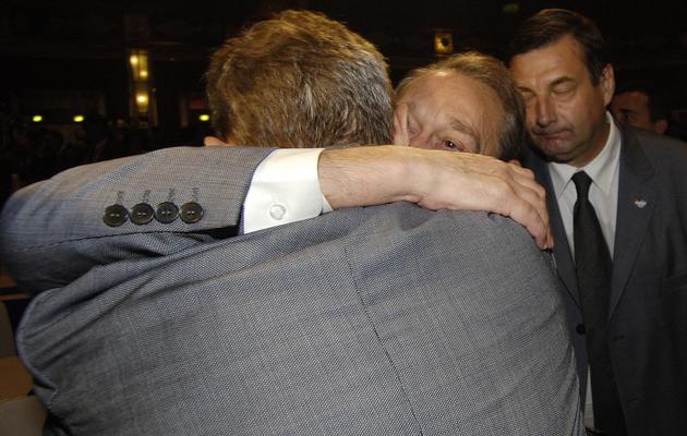 Le maire de Paris Bertrand Delanoë console un membre de la délégation française, aux côtés du ministre des Sports Jean-François Lamour, après l'annonce que Londres accueillerait les JO 2012, le 6 juillet 2005 à Singapour [Eric Feferberg / AFP]