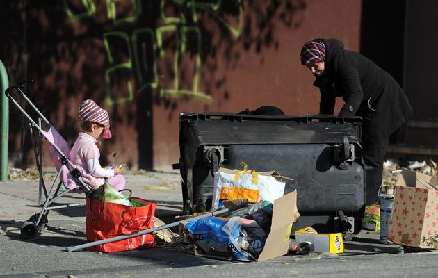 Une femme fouille des poubelles, avec son enfant dans une poussette [Gerard Julien / AFP/Archives]