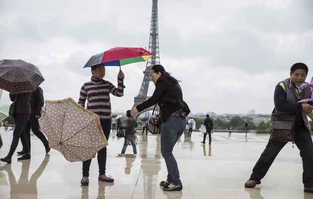 Des touristes s'accrochent à leurs parapluies sur la place du Trocadéro, le 20 mai 2013 [Fred Dufour / AFP]
