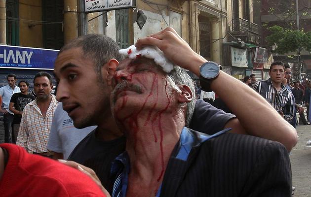 Un Egyptien aide un homme blessé lors d'affrontements avec des Coptes au Caire le 7 avril 2013 [ / AFP]