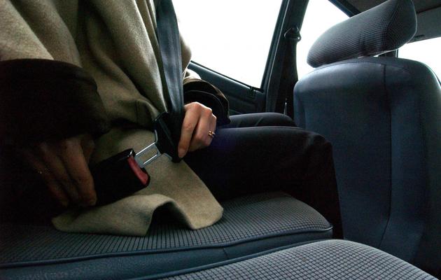 Une personne attache sa ceinture de sécurité à l'arrière d'un véhicule [Mychele Daniau / AFP/Archives]