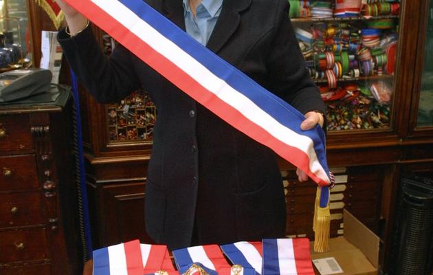 Une vendeuse présente présente des écharpes municipales, le 06 mars 2000 dans une boutique à Paris [Patrick Kovarik / AFP/Archives]