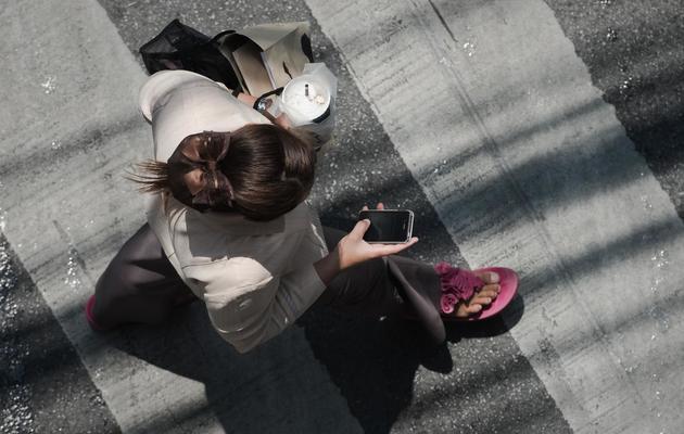 Une femme consulte son smartphone dans la rue [Nicolas Asfouri / AFP/Archives]