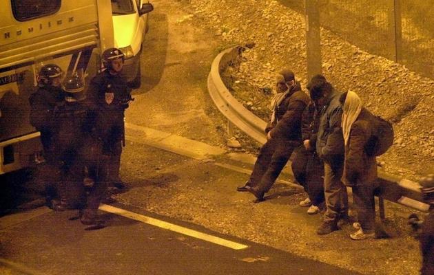 Des CRS surveillent, dans la nuit du 25 au 26 décembre 2001 à Coquelles, des clandestins du centre de la Croix Rouge de Sangatte qui avaient pénétré dans le terminal fret d'Eurotunnel [Denis Charlet / AFP/Archives]