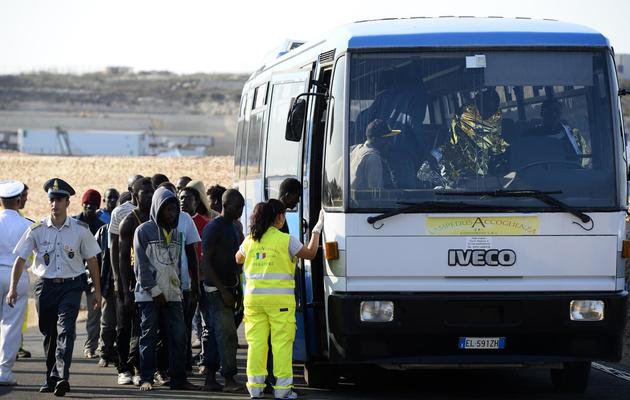 Des migrants, arrivés en bateau le 8 juillet 2013 à Lampedusa, montent à bord d'un car [Andreas Solaro / AFP]