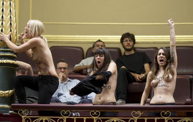Members of feminist movement Femen shout during a pro-life demonstration staged inside the house of congress in Madrid on October 9, 2013. Three bare chested activists interrupted today the house of congress gathering shouting from aisle stands "Abortion is sacred" forcing the president of the chamber, Jesus Posada, to halt the session and order their eviction. AFP PHOTO / DANI POZO [DANI POZO / AFP]