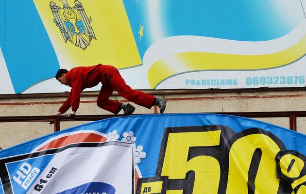Un ouvrier installe un panneau publicitaire sous les drapeaux moldave et gagaouze à Comrat, principale ville de Gagaouzie, le 6 avril 2014 [Daniel Mihailescu / AFP]