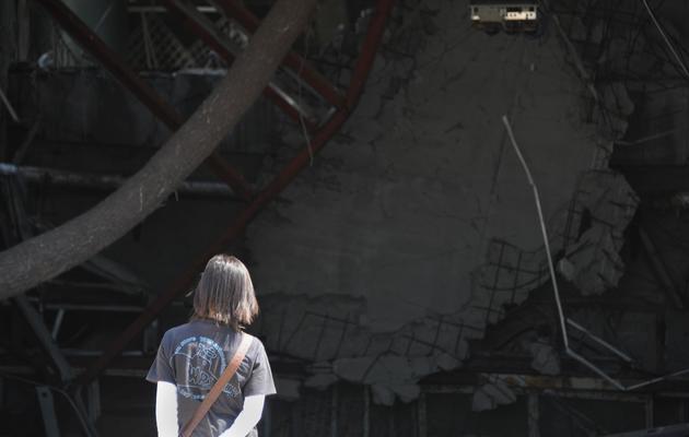 Un touriste observe les ruines d'un bâtiment endommagé par le tsunami de 2011 à Rikuzentakata le 20 juillet 2013 [Toru Yamanaka / AFP]