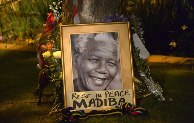 Un portrait de Nelson Mandela entouré de fleurs après l'annonce de son décès, le 6 décembre 2013 à Johannesburg [Alexander Joe / AFP]