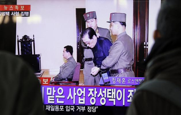 Des Sud-Coréens regardent à la télévision le 12 décembre 2013 à Séoul, Jang Song-thaek emmené par des gardes à la sortie du tribunal peu avant son éxécution  [Woohae Cho  / AFP]