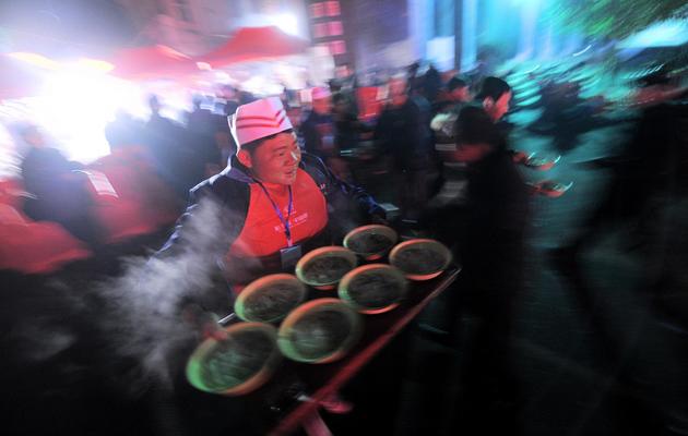 Un homme sert des bols de nouilles traditionnelles, offert aux Chinois à l'occasion du 120e anniversaire de la naissance de Mao Tsa-toung le 26 décembre 2013 à Shaoshan, sa ville natale [Wang Zhao / AFP]