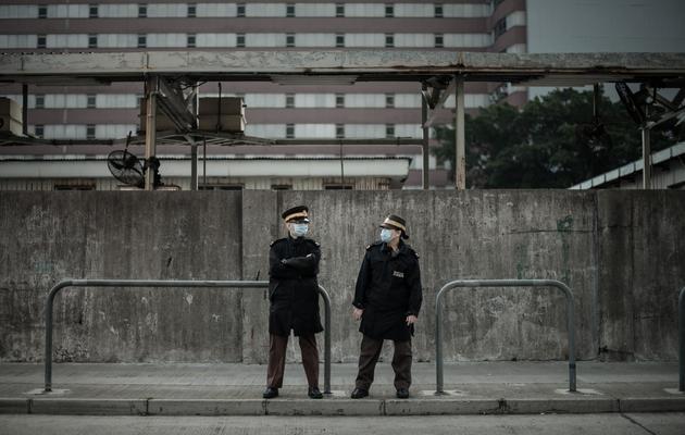 Deux gardes devant le marché aux volailles fermé de Cheung Sha Wan, à Hong Kong, le 28 janvier 2014 [Philippe Lopez / AFP]