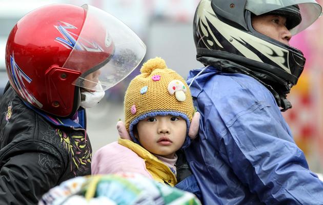 Une famille chinoise à moto s'arrête pour une pause à Wuzhou, le 25 janvier 2014 [STR / AFP]