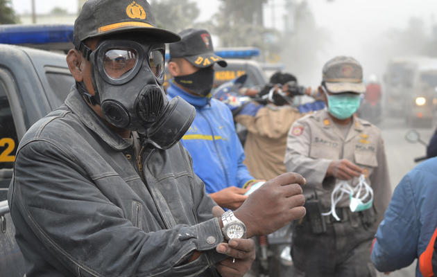 Des policiers distribuent des masques aux habitants de Malang, après l'éruption du mont Kelud, le 14 février 2014 sur l'île de Java, en Indonésie [Aman Rochman / AFP]