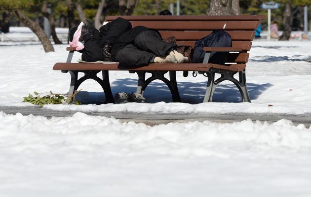 Un homme sans-abri recroquevillé sur un banc le 16 février 2014 à Tokyo enneigé  [Toru Yamanaka / AFP]