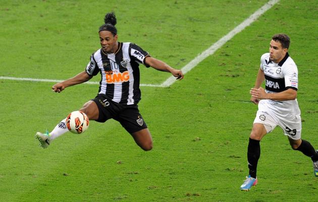 Le Brésilien  de l'Atletico Mineiro Ronaldinho (g) tente de contrôler le ballon face à un défenseur d'Olimpia, le 24 juillet 2013 à Belo Horizonte [ / AFP]