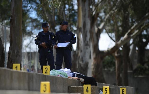 Des policiers guatémaltèques se tiennent près du corps d'un adolescent de 16 ans abattu par un gang, près de la capitale, le 13 juin 2013 [Johan Ordonez / AFP/Archives]