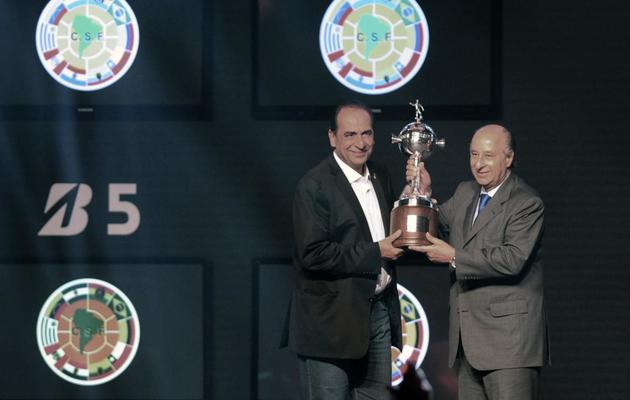 Le président de l'Atletico Mineiro president Alexandre Kalil (g) soulève le trophée de la Copa Libertadores remporté par son équipe, lors du tirage au sort de la 55e édition de l'épreuve, le 12 décembre 2013 à Luque au Paraguay [ / AFP/Archives]