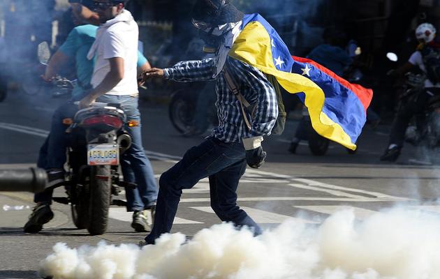 Un opposant au président vénézuélien Nicolas Maduro retourne une grenade lacrymogène lors d'une manifestation à Caracas le 22 mars 2014 [Juan Barreto / AFP]