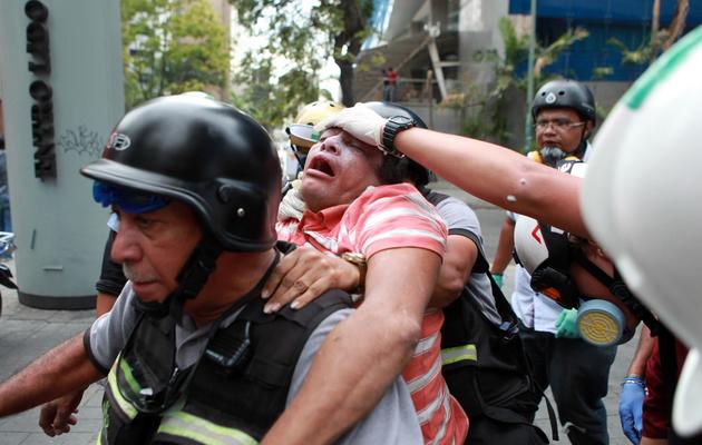 Un pompier aide un manifestant qui proteste contre le gouvernement de Nicolas Maduro à Caracas le 1er avril 2014 [Federico Parra / AFP]