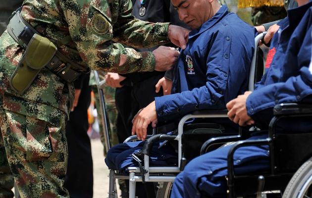 Le chef d'état-major des Forces armées colombiennes, le général Javier Alberto Florez (c), décore un soldat blessé, à Bogota le 9 avril 2014, lors de la journée nationale des victimes du conflit armé [Guillermo Legaria / AFP]