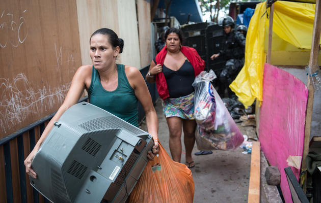 Des squatteurs qui occupaient une parcelle inoccupée portent leurs affaires après avoir été évacués par la police le 11 avril 2014 à Rio de Janeiro [Yasuyoshi chiba / AFP]