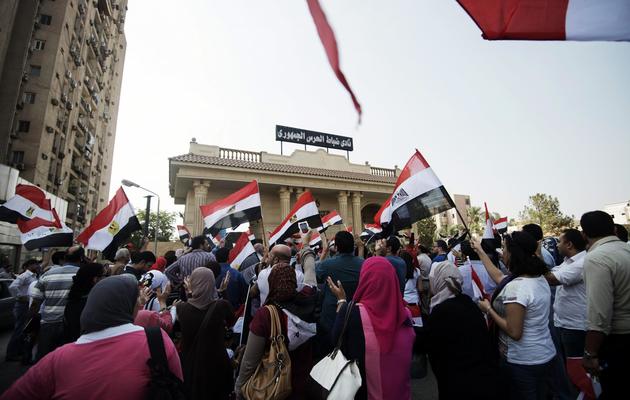 Des manifestants égyptiens anti-Morsi agitant le drapeau national devant le bâtiment des Gardes républicains, le 3 juillet 2013 au Caire  [Gianluigi Guercia / AFP]