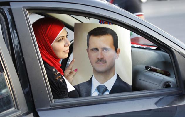 Une femme tient le portrait du président syrien Bachar al-Assad à Damas, le 11 septembre 2013 [Anwar Amro / AFP]