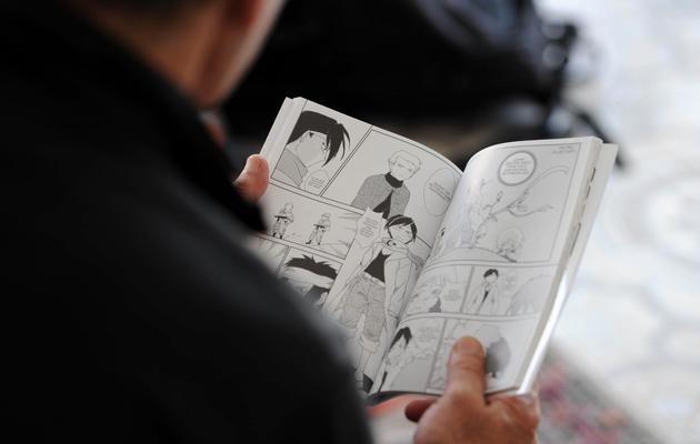 Un homme lit "La révolution", un manga créé par l'artiste algérienne Fella Matougui, le 17 septembre 2013 à Alger [Farouk Batiche / AFP]