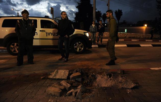Des soldats et des civils israéliens près d'un trou causé par une roquette à Sderot le 12 mars 2014 [David Buimovitch / AFP]