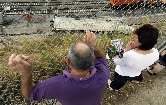 Deux personnes le 27 juillet 2013 à Angrois devant la locomotive du train qui a déraillé près de Saint-Jacques de Compostelle [Rafa Rivas / AFP]