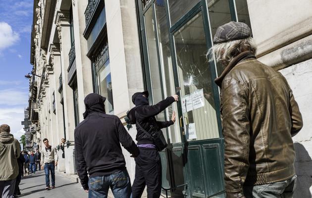 Un homme casse la vitre d'une banque, lors d'une manifestation contre le fascisme et en l'honneur de la mémoire de Clément Méric, le 23 juin 2013 à Paris [Fred Dufour / AFP]