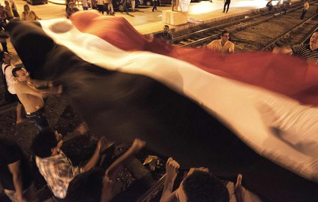 Des opposants au président Morsi portent le drapeau national, le 29 juin 2013, devant le palais présidentiel au Caire [Gianluigi Guercia / AFP]