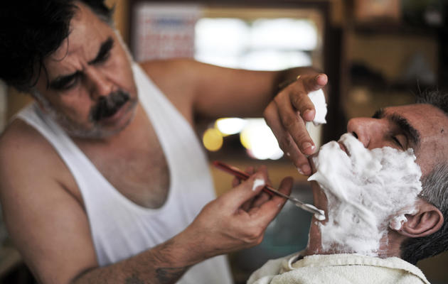 Un barbier turc Mehmet Haskan (g) rase un client dans son salon le 19 juillet 2013 à Istanbul [OZAN KOSE / AFP]