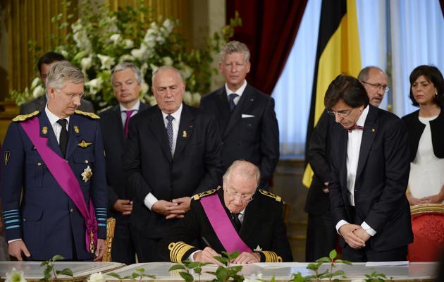 Albert II (c) signe le 21 juillet 2013 à Bruxelles son acte d'abdication en faveur de son fils Philippe, présent à ses côtés (g) [DIRK WAEM / BELGA/AFP]