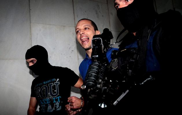 Ilias Kasidiaris entouré de policiers masqués à la sortie des locaux de la police le 28 septembre 2013 à Athènes [Panagiotis Tzamaros / AFP/Archives]