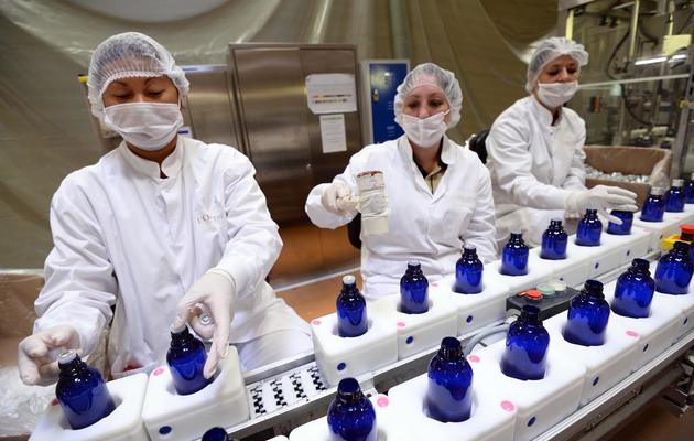 Des employées vérifient les bouteilles pour les huiles essentielles de la marque L'Occitane, le 24 octobre 2013 à Manosque, dans le sud-est de la France [Anne-Christine Poujoulat / AFP]