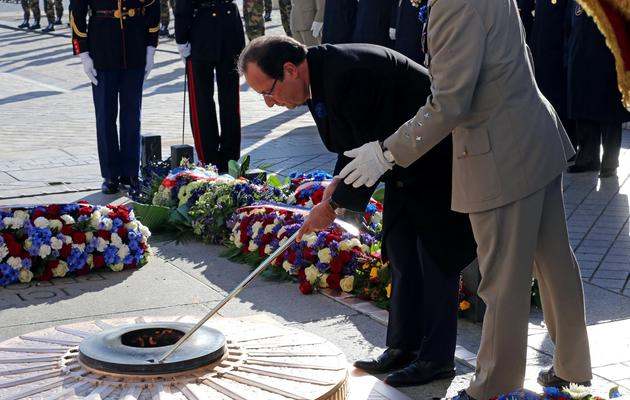 François Hollande (c) ravive la flamme au soldat inconnu, le 11 novembre 2013 à Paris [Rémy de la Mauviniere / Pool/AFP]