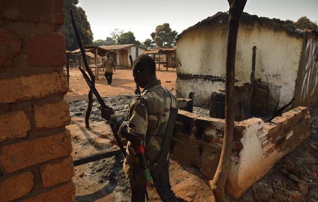 Un combattant anti-Balaka marche à côté de maisons brûlées par l'ex-Seleka, dans la ville de Bogoura, à 60km au nord de Bangui, le 19 janvier 2014 [Eric Feferberg / AFP]