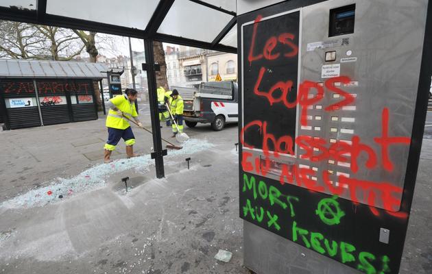 Des employés municipaux ramassent des débris de verre d'une station de tramway endommagée par des manifestants, le 23 février 2014 à Nantes [Frank Perry / AFP]
