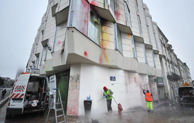 Des employés municipaux nettoient des tags sur la façade d'un poste de police à Nantes, le 23 février 2014 [Frank Perry / AFP]