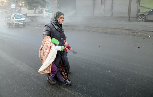 Une Syrienne blessée marche avec ses deux enfants après des raids de l'armée de l'air à Alep, le 15 décembre 2013 [ / Mohammed Al-Khatieb/AFP]