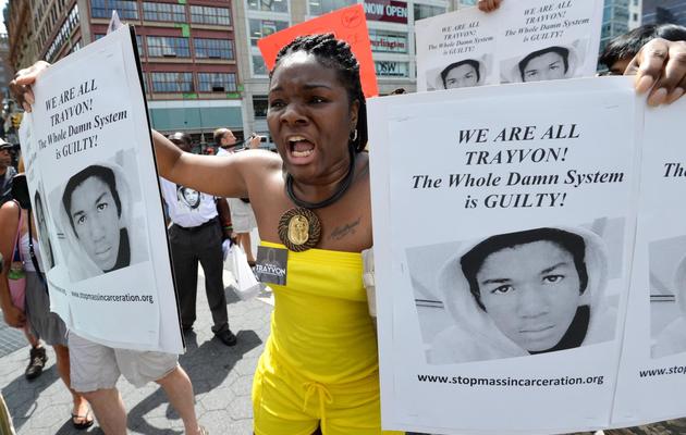 Une femme manifeste à New York en tenant à la main des portraits de Trayvon Martin, après l'acquittement de George Zimmerman, le 14 juillet 2013 [Stan Honda / AFP]