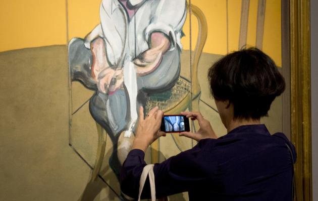 Une personne photographie une partie du triptyque du peintre britannique Francis Bacon consacré à Lucian Freud exposé chez Christie's, le 31 octobre 2013 à New York [Don Emmert / AFP/Archives]