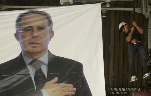un homme installe une bannière à l'image de l'ancien président colombien Alvaro Uribe, à Medellin le 2 février 2014  [Raul Arboleda / AFP/Archives]