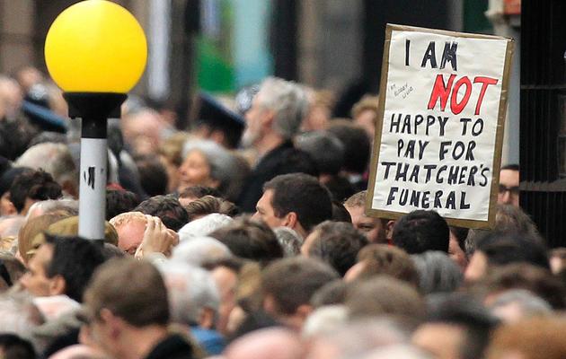 "Pas heureux de payer pour les funérailles de Thatcher" est écrit sur une pancarte au milieu des badauds le 17 avril 2013 à Londres [Matt Dunham / Pool/AFP]