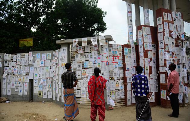 Des personnes regardent les photos des centaines d'ouvriers portés disparus après l'effondrement d'un immeuble au Bangladesh, le 4 mai 2013 [Munir Uz Zaman / AFP]